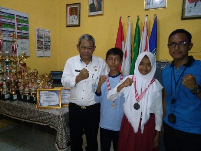 
					Kodrat (kanan) guru olahraga bersama Rohmat (kiri) Kasek SDN Serua 03 dan para atlet berprestasi. (FOTO : Sudibyo/Harian Sederhana)