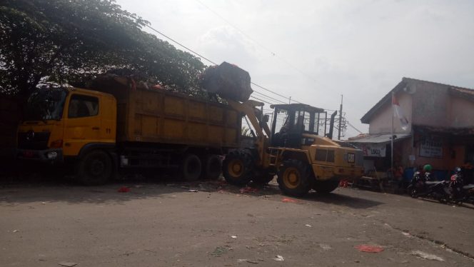 
					Sebuah alat berat tengah mengangkat sampah ke dump truk. (FOTO : Aji Hendro/Harian Sederhana)