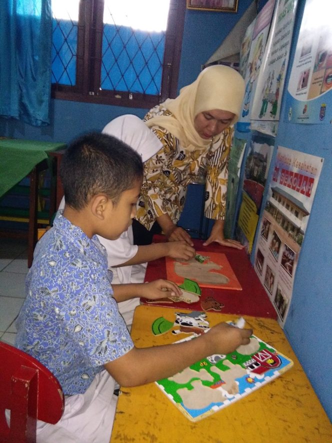 
					Ika Kurniawati, guru pembimbing khusus tengah mengajarkan siswa ABK di ruang kelas di SDN Bojongsari 01. (FOTO : Sudibyo/Harian Sederhana)