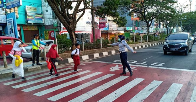 
					Petugas Penyeberang Jalan SDN Poncin 1 bersama petugas Dishub membantu siswa menyeberang.