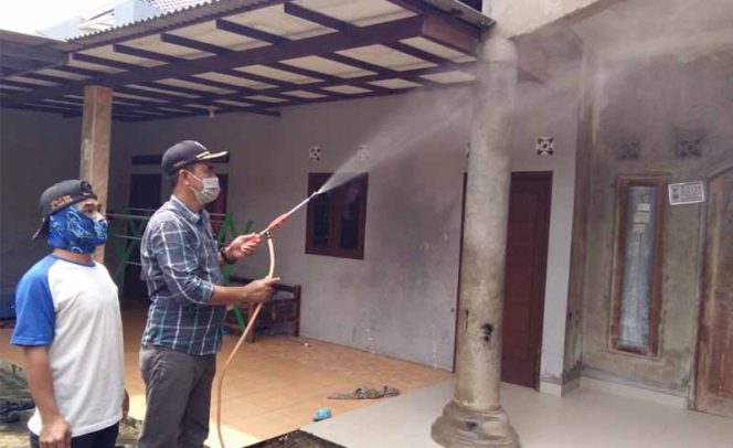 
					Ketua RW 04, Hambali sedang menyemprot disinfektan di depan rumah warga.