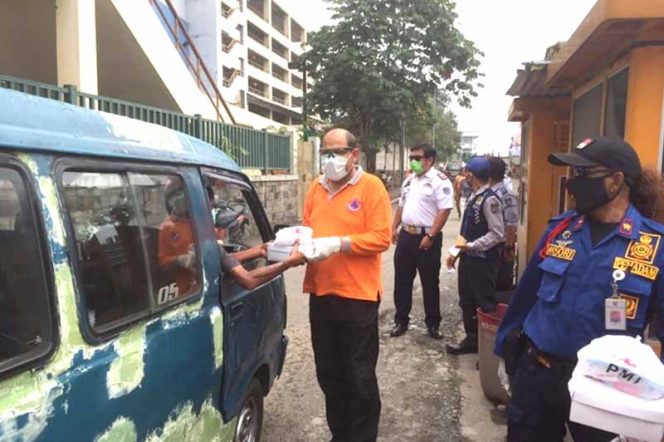 
					Denny Romulo, Kabid Penanggulangan Bencana Damkar sedang memberikan nasi box kepada sopir angkot.