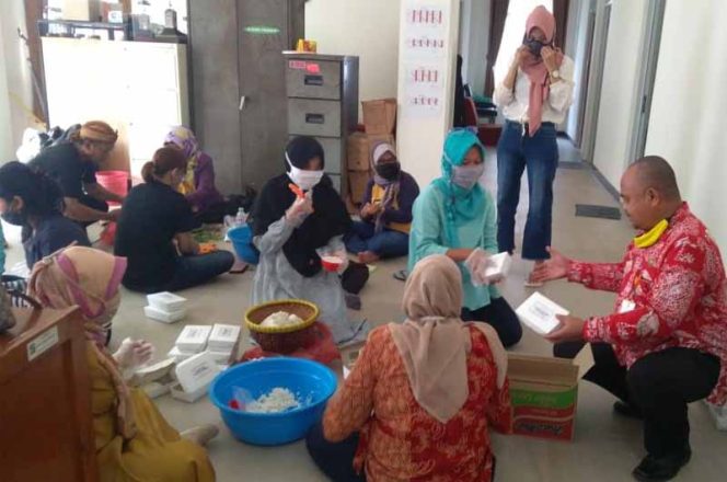 
					Ibu-ibu Kader Tim Penggerak PKK Kelurahan Sempur yang sedang menyusun bahan masakan dan nasi putih ke dalam setiap box.